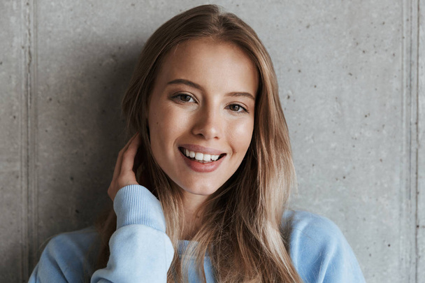 Picture of young cheerful happy pretty woman standing over grey wall background looking camera. - Valokuva, kuva