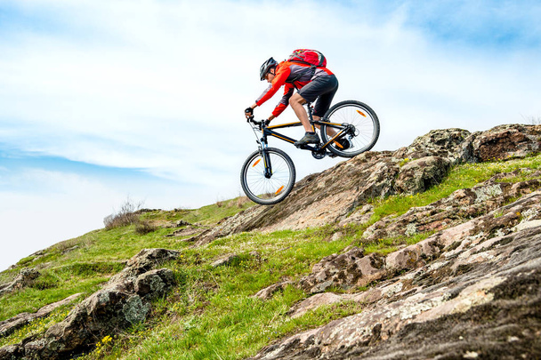 Fietser in Red Jacket Rijden op de mountainbike naar beneden Rocky Hill. Extreme Sport en Avontuur Concept. - Foto, afbeelding
