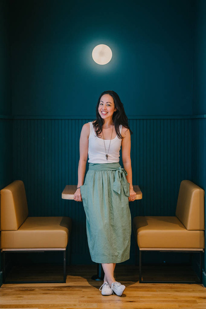 full length portrait of stylish woman smiling leaning on table in modern office  - Foto, afbeelding