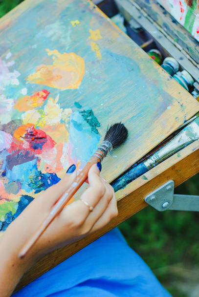 Fechar-se de pincel em mãos de mulher misturando pinturas na paleta - Foto, Imagem