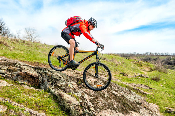 Rowerzysta w czerwonej kurtce na rowerze górskim w dół Rocky Hill. Ekstremalne Sport i przygoda Concept. - Zdjęcie, obraz