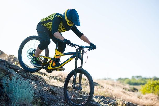 Επαγγελματίας ποδηλάτης Riding the Downhill Mountain Bike στο Summer Rocky Trail το βράδυ. Extreme Sport και Enduro Cycling Concept. - Φωτογραφία, εικόνα