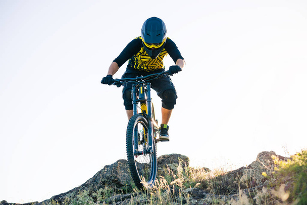 Professional Cyclist Riding the Downhill Mountain Bike on the Summer Rocky Trail at the Evening. Extreme Sport and Enduro Cycling Concept. - Foto, Imagen
