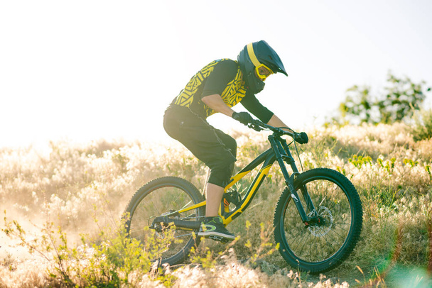 Professional Cyclist Riding the Downhill Mountain Bike on the Summer Rocky Trail at the Evening. Extreme Sport and Enduro Cycling Concept. - Foto, imagen