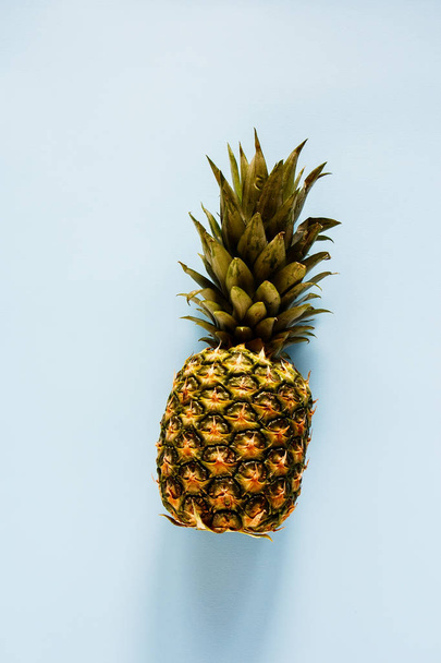 Pineapple on blue background flat lay. Tropical fruit. Useful natural organic food. One whole object. Style minimalist. Top view - 写真・画像