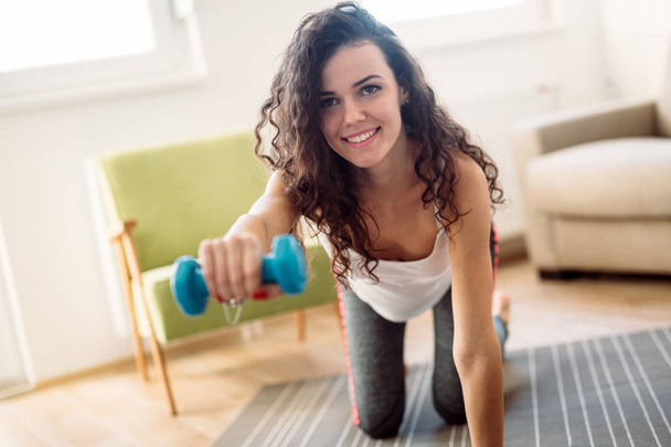 Young attractive sportswoman doing fitness exercises at home - Fotó, kép