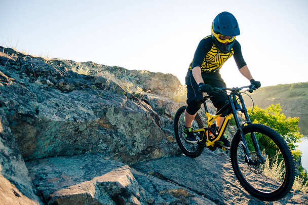Επαγγελματίας ποδηλάτης Riding the Downhill Mountain Bike στο Summer Rocky Trail το βράδυ. Extreme Sport και Enduro Cycling Concept. - Φωτογραφία, εικόνα