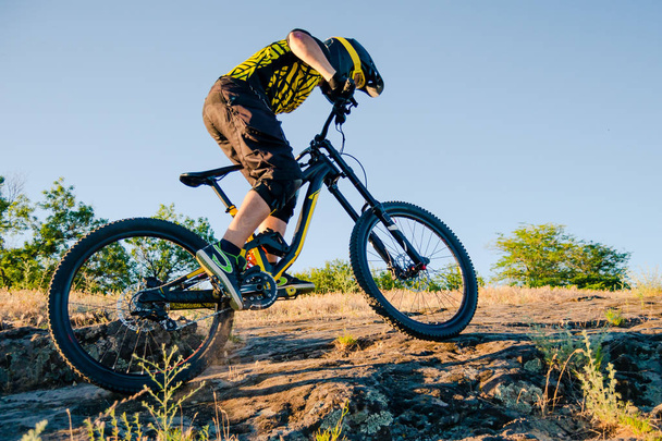 Professional Cyclist Riding the Downhill Mountain Bike on the Summer Rocky Trail at the Evening. Extreme Sport and Enduro Cycling Concept. - Foto, immagini