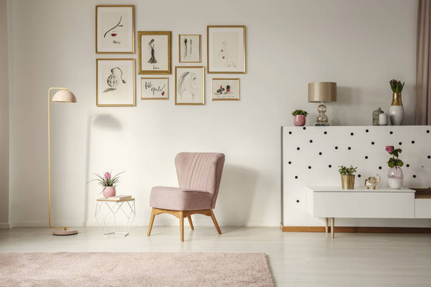 Old-fashioned armchair, pastel pink floor lamp and stylish, golden decorations in a retro living room interior with white walls - Zdjęcie, obraz