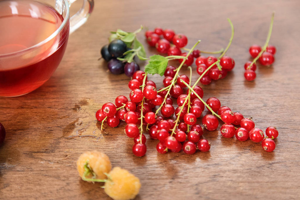 Red Currants, Black Currants, Raspberries. Ripe Berries and red Juice Glass on Wooden Table. Food Concept.Homemade Compote - Фото, изображение