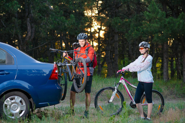 Young Couple Unmounting Mountain Bikes from Bike Rack on the Car. Adventure and Family Travel Concept. - Foto, Bild
