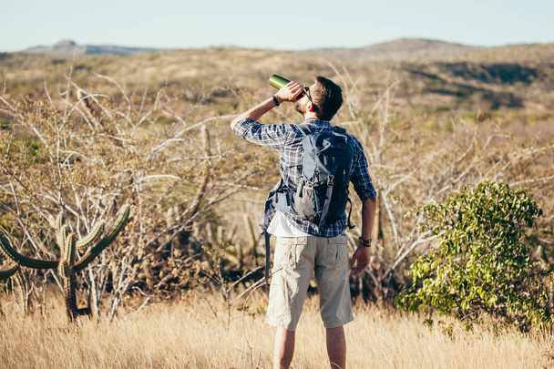 Man taking a break to drink from water bottle while hiking at Brazilian Caatinga - Photo, Image