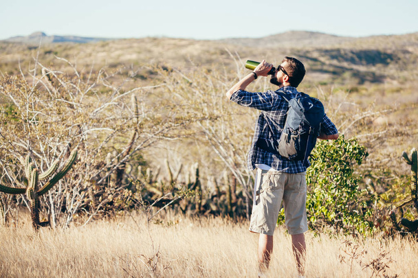 Man taking a break to drink from water bottle while hiking at Brazilian Caatinga - Photo, Image