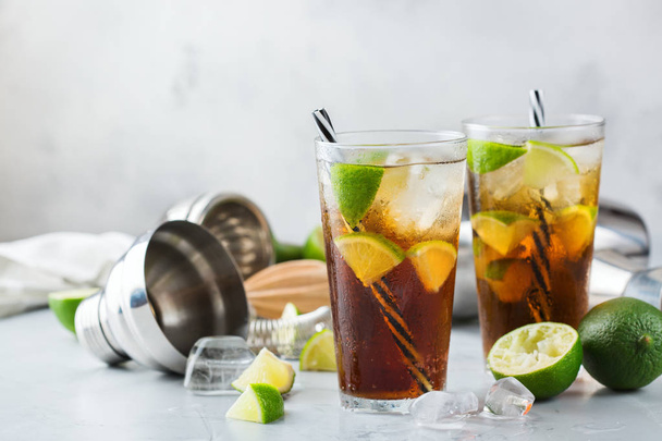 Food and drink, holidays party concept. Cuba libre or long island iced tea alcohol cocktail drink beverage, longdrink in a glass with straw, ice and lime on a table - Fotoğraf, Görsel