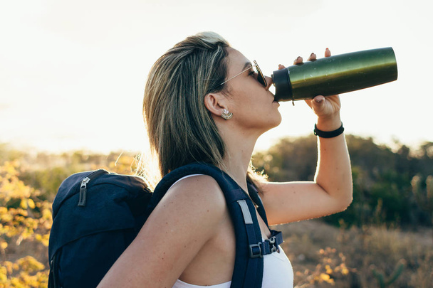 Woman taking a break to drink from water bottle while hiking at Brazilian Caatinga - Photo, Image