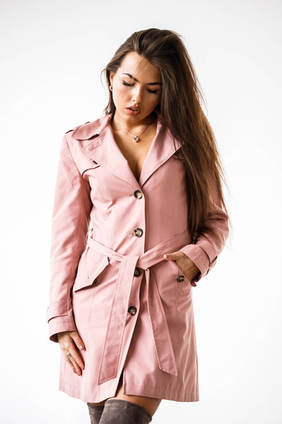 Portrait of beautiful brunette woman wearing pink coat standing on white studio background - Foto, Imagen