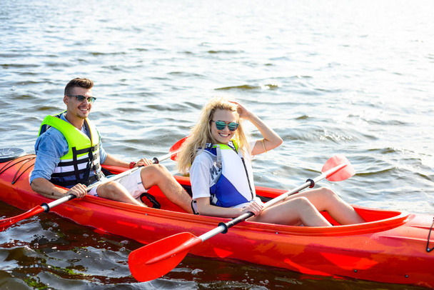 Young Happy Couple Paddling Kayak on the Beautiful River or Lake - Фото, изображение