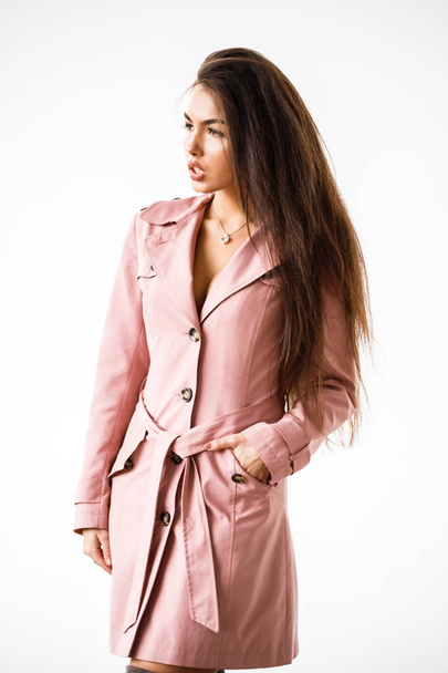Portrait of beautiful brunette woman wearing pink coat standing on white studio background - Fotoğraf, Görsel