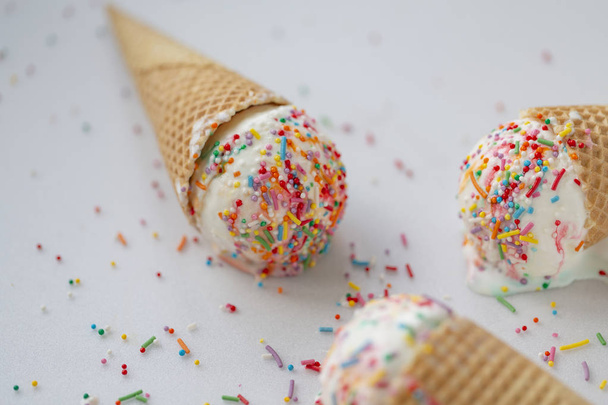 Waffle cone with white ice cream and sweet sprinkles on a light background - Foto, immagini