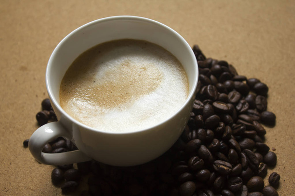 Melkschuim in koffiemokken en koffiebonen - Foto, afbeelding