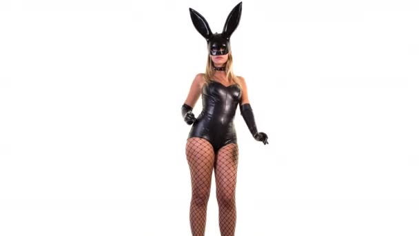 Atractiva mujer bailando con gran máscara de orejas de conejo y cuerpo de látex negro sobre fondo blanco
 - Metraje, vídeo
