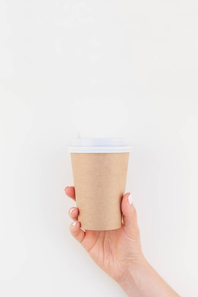 Image créative simulée de femme tenant à la main une tasse à café en papier artisanal avec espace de copie isolé sur fond blanc dans un style minimaliste. Modèle pour blog féminin, médias sociaux
 - Photo, image