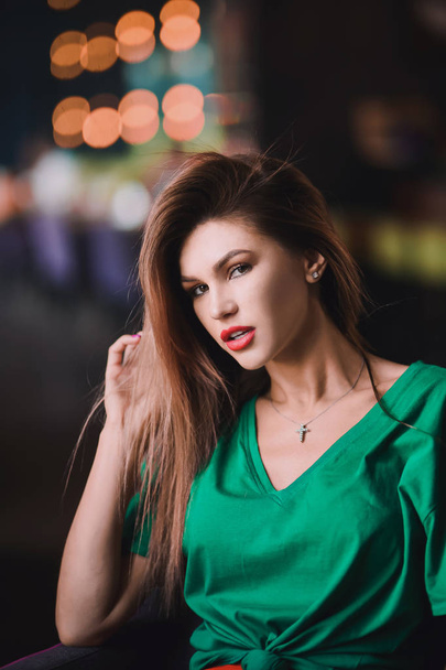 Emotional portrait of Fashion stylish sexy of  young hipster blonde woman, elegant lady, green top and red skirt, cool  girl. City view  urban lifestyle dark cafe background. - Foto, afbeelding