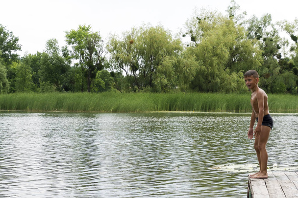 Νεαρό αγόρι ετοιμάζεται να πηδά στην λίμνη, καλοκαιρινή διασκέδαση - Φωτογραφία, εικόνα