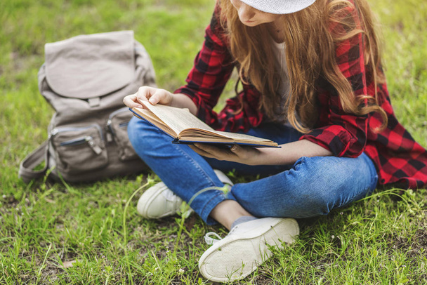 Dziewczyna siedzi i czytanie książki na trawie - Zdjęcie, obraz