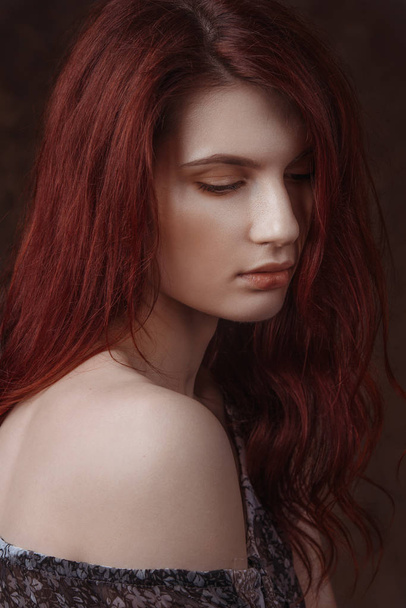 Dramatic retro portrait of a young beautiful dreamy redhead woman. Soft vintage toning - 写真・画像