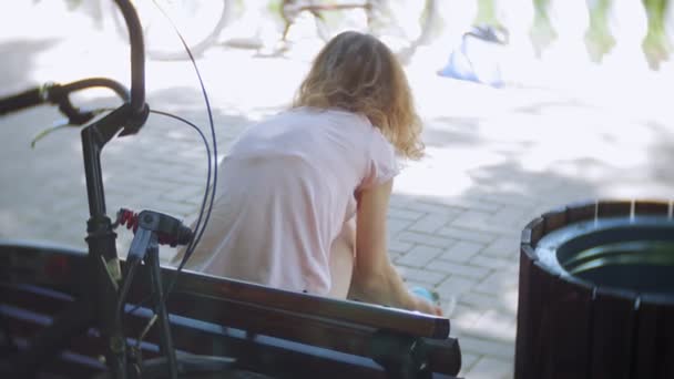 Tekerlekli paten parkta bankta oturan kadın Giydir - Video, Çekim