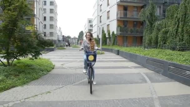 Young woman riding on bike and drinking coffee or tea. Beautiful summertime mood shot of young woman or girl riding bicycle in city. Girl with cerly hair riding on bike home. 60 fps - Filmati, video