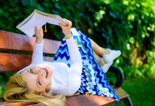 Леди счастливое лицо любит читать. Время самосовершенствоваться. Девушка лежала скамейка парк отдыха с книгой, зеленый фон природы. Женщина проводит досуг с книгой. Девушка читает на открытом воздухе во время отдыха на скамейке
 - Фото, изображение