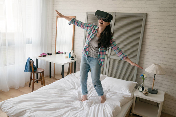 Asian childish woman wearing her VR device and open her arms as like she is a bird flying in the sky. - Foto, imagen