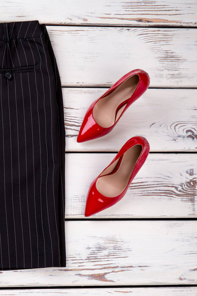 Κόκκινα ψηλοτάκουνα παπούτσια και μαύρο παντελόνι, το top view. - Φωτογραφία, εικόνα