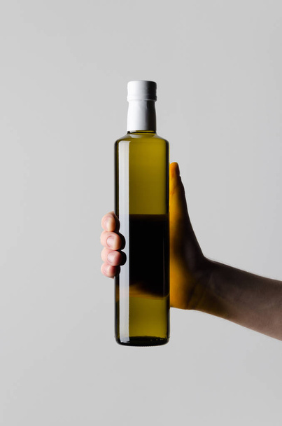 Olive / Sunflower / Sesame Oil Bottle Mock-Up - Male hands holding a oil bottle on a gray background - Fotó, kép