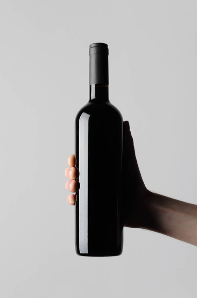 Wine Bottle Mock-Up - Male hands holding a wine bottle on a gray background - 写真・画像