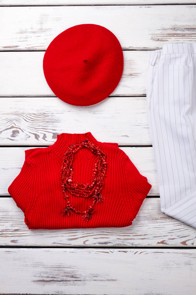 Διπλωμένο κόκκινο πουλόβερ και berete καπέλο. - Φωτογραφία, εικόνα