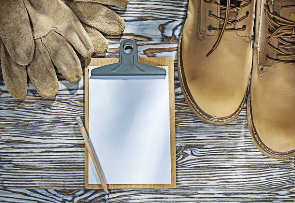 Safety boots gloves pencil clipboard on wooden board - Fotó, kép