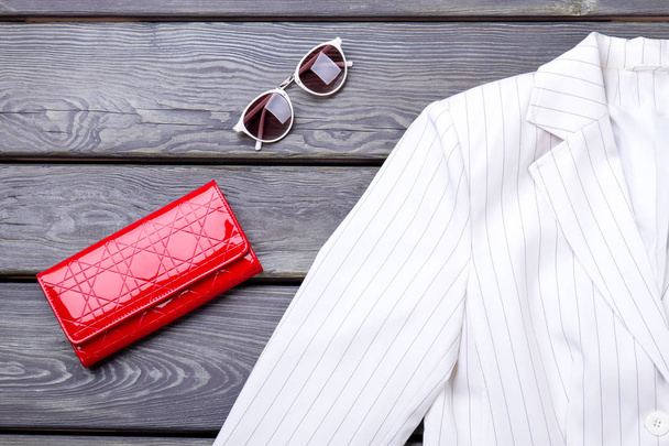 Gros plan veste blanche, portefeuille rouge et lunettes de soleil
. - Photo, image