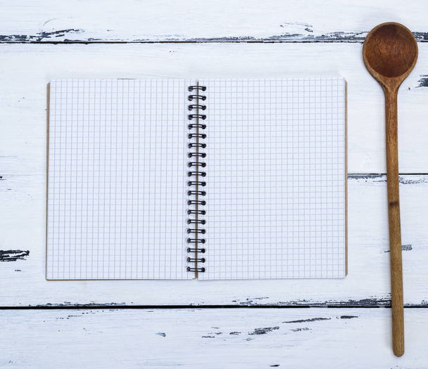 open empty notebook in a box and a kitchen spoon on the table, top view - Photo, Image