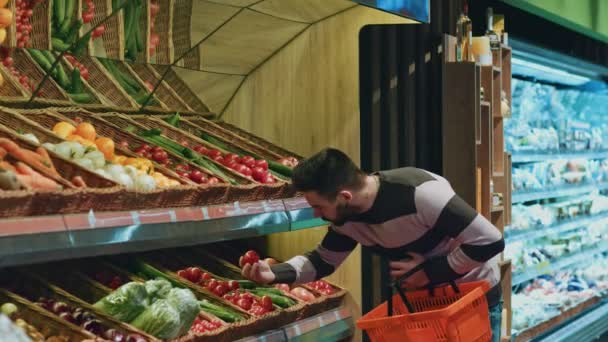 Aufnahme eines gutaussehenden jungen Mannes, der nachdenklich in die Supermarktregale blickt und Gemüse auswählt. - Filmmaterial, Video