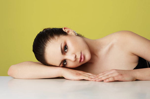 Beautiful young woman with big brown eyes and dark eyebrows relaxing over empty yellow studio background.Model with light nude make-up.Copy paste space,close up.Healthcare skin concept. - Φωτογραφία, εικόνα