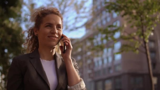 Mujer encantadora pelo rizado tiene una conversación positiva en el teléfono
 - Metraje, vídeo