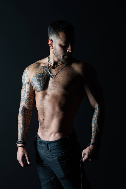 Bodycare with fitness and sport. Man with tattooed arm and chest. Bearded man with strong torso. Tattoo model with sexy belly. Sportsman or athlete in fashion jeans - Fotó, kép