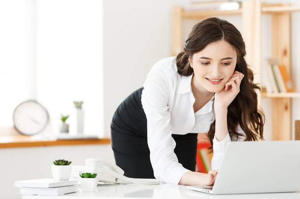 Muotokuva kaunis nuori nainen opiskelee tai työskentelee seisoessaan kannettavan tietokoneen ja kannettavan
 - Valokuva, kuva