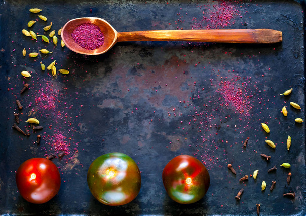 黒トマト cumato とスパイス ウルシの木のスプーン。オーガニック製品やビンテージさびた金属を背景にスパイスのコンセプトです。健康食品、菜食主義者やダイエット栄養の概念 - 写真・画像