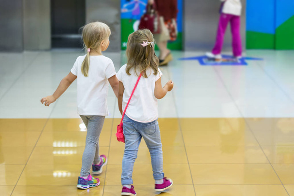 Twee schattige blonde kleine meisjes lopen samen in winkelcentrum. Paar jongen vrienden hand in hand tijdens wandeling. Peuter vriendschap in een jeugd. - Foto, afbeelding