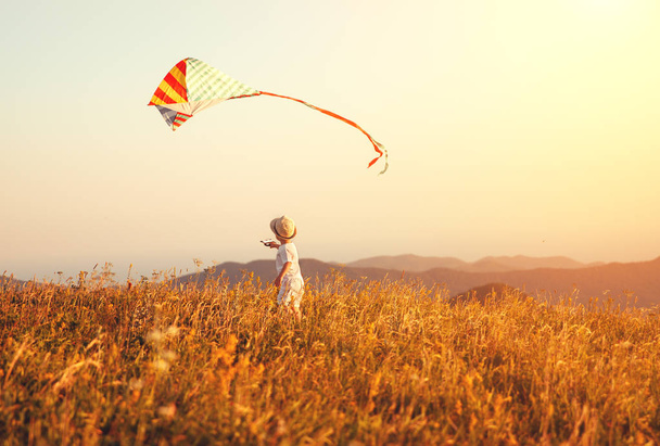 夕暮れ屋外凧と走っている幸せな子供少年 - 写真・画像