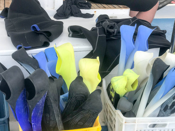 Plastic doos, mand met multi-gekleurde rubber duiken flippers voor zwemmen, duiken apparatuur aan boord van een doos, boot, cruise liner. - Foto, afbeelding